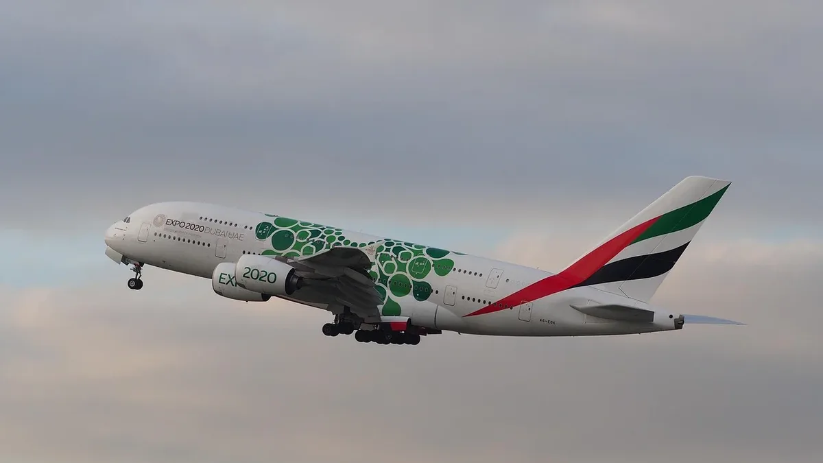 An Emirates Airbus A380-800 aircraft in flight, with the plane's distinctive green and red livery visible.